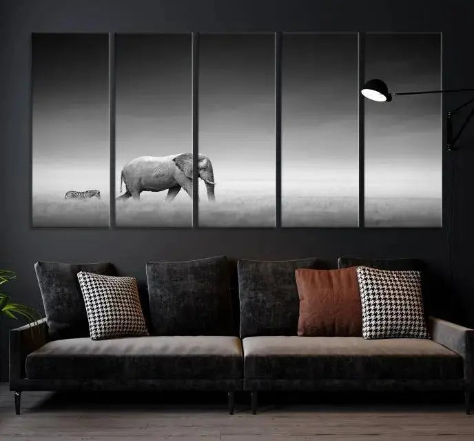 Elephant and Zebra Wall Art Canvas Print: A black and white triptych on museum-quality canvas, showcasing an elephant and zebra walking across a grassy plain. Equipped with a UV-protective coating for lasting protection.