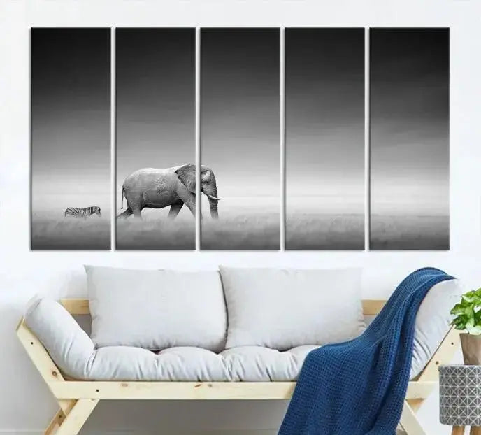 Elephant and Zebra Wall Art Canvas Print: A black and white triptych on museum-quality canvas, showcasing an elephant and zebra walking across a grassy plain. Equipped with a UV-protective coating for lasting protection.