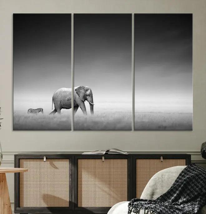 Elephant and Zebra Wall Art Canvas Print: A black and white triptych on museum-quality canvas, showcasing an elephant and zebra walking across a grassy plain. Equipped with a UV-protective coating for lasting protection.