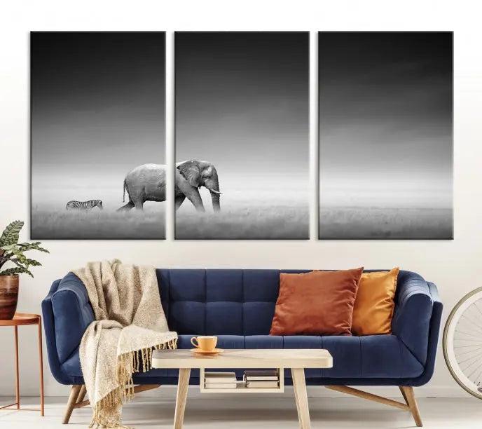 Elephant and Zebra Wall Art Canvas Print: A black and white triptych on museum-quality canvas, showcasing an elephant and zebra walking across a grassy plain. Equipped with a UV-protective coating for lasting protection.