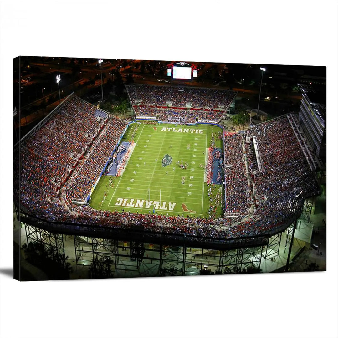 The wall art is a triptych canvas depicting the Florida Atlantic University Owls Football Team at the Boca Raton FAU Stadium, offering a gallery-quality finish.