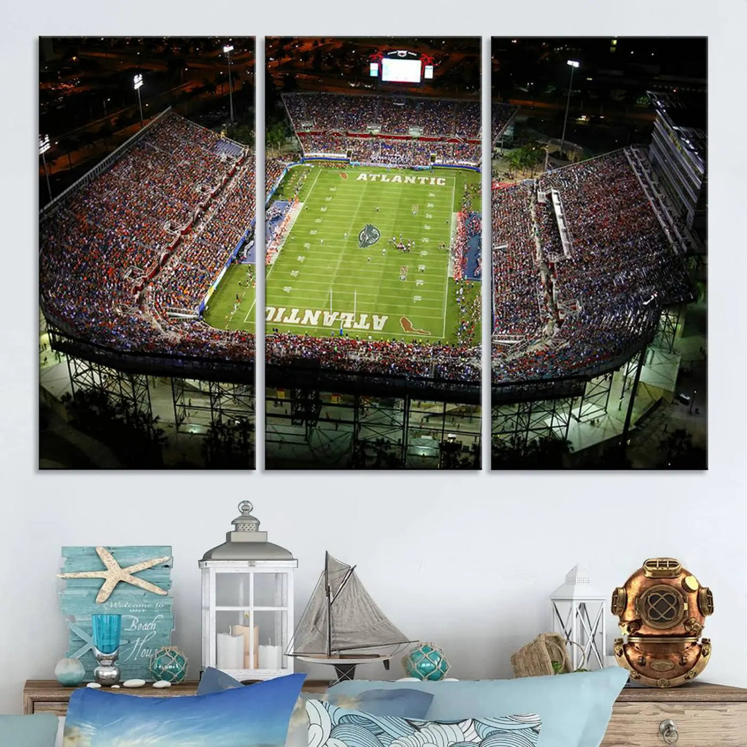 The wall art is a triptych canvas depicting the Florida Atlantic University Owls Football Team at the Boca Raton FAU Stadium, offering a gallery-quality finish.