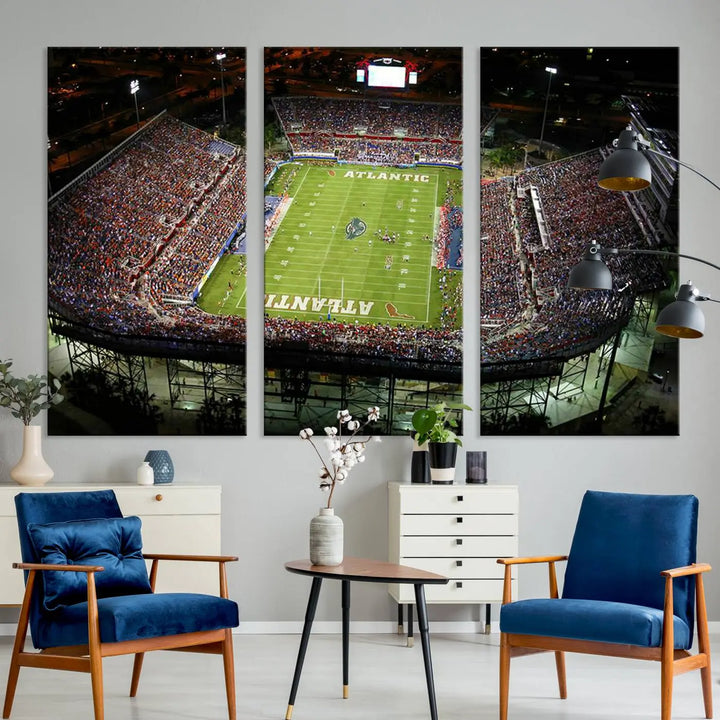 The wall art is a triptych canvas depicting the Florida Atlantic University Owls Football Team at the Boca Raton FAU Stadium, offering a gallery-quality finish.