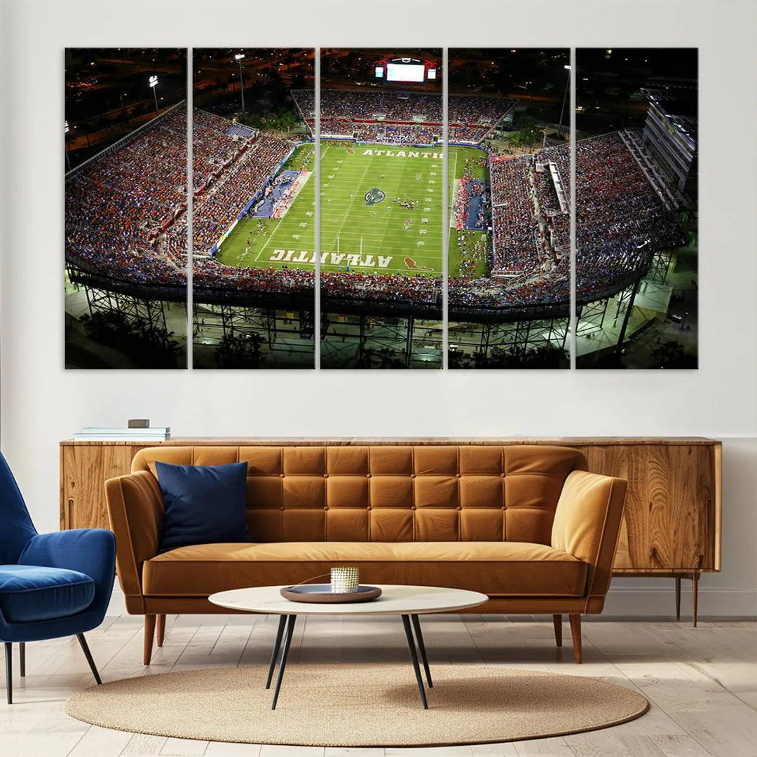 The wall art is a triptych canvas depicting the Florida Atlantic University Owls Football Team at the Boca Raton FAU Stadium, offering a gallery-quality finish.