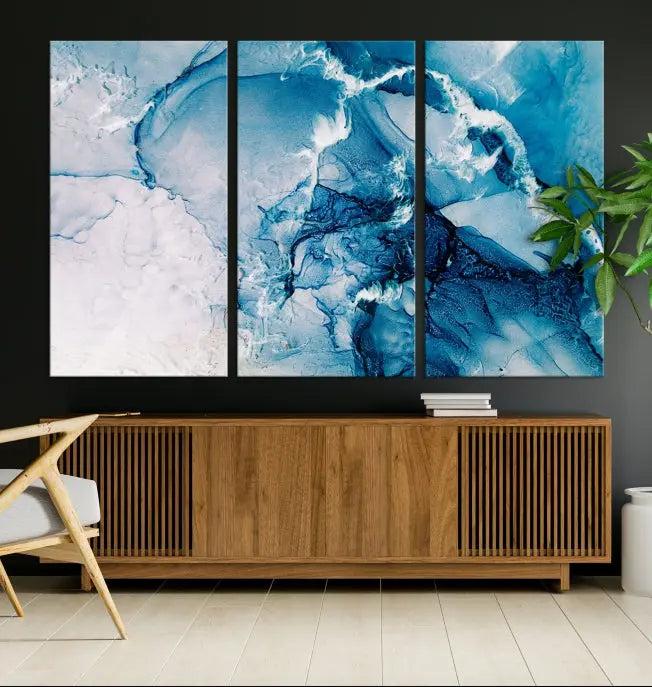 A set of Fluid Effect Wall Art Abstract Canvas prints, showcasing blue and white abstract designs on museum-quality canvas, is tastefully arranged on a dark wall.