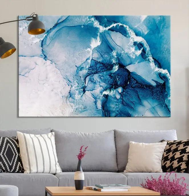 A set of Fluid Effect Wall Art Abstract Canvas prints, showcasing blue and white abstract designs on museum-quality canvas, is tastefully arranged on a dark wall.