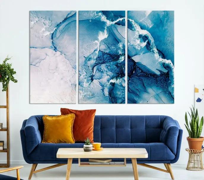 A set of Fluid Effect Wall Art Abstract Canvas prints, showcasing blue and white abstract designs on museum-quality canvas, is tastefully arranged on a dark wall.