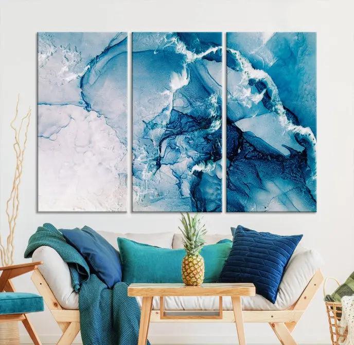 A set of Fluid Effect Wall Art Abstract Canvas prints, showcasing blue and white abstract designs on museum-quality canvas, is tastefully arranged on a dark wall.