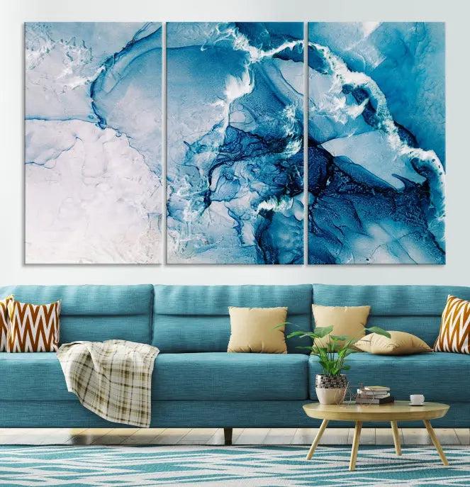 A set of Fluid Effect Wall Art Abstract Canvas prints, showcasing blue and white abstract designs on museum-quality canvas, is tastefully arranged on a dark wall.