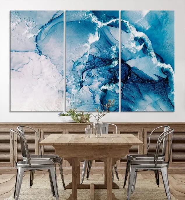 A set of Fluid Effect Wall Art Abstract Canvas prints, showcasing blue and white abstract designs on museum-quality canvas, is tastefully arranged on a dark wall.