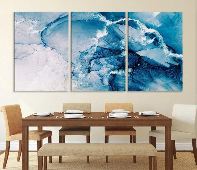 A set of Fluid Effect Wall Art Abstract Canvas prints, showcasing blue and white abstract designs on museum-quality canvas, is tastefully arranged on a dark wall.