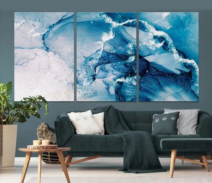 A set of Fluid Effect Wall Art Abstract Canvas prints, showcasing blue and white abstract designs on museum-quality canvas, is tastefully arranged on a dark wall.