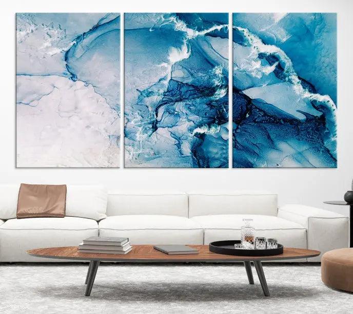 A set of Fluid Effect Wall Art Abstract Canvas prints, showcasing blue and white abstract designs on museum-quality canvas, is tastefully arranged on a dark wall.