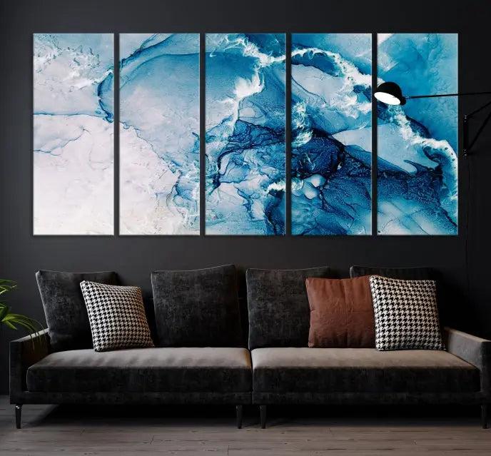 A set of Fluid Effect Wall Art Abstract Canvas prints, showcasing blue and white abstract designs on museum-quality canvas, is tastefully arranged on a dark wall.