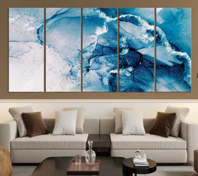 A set of Fluid Effect Wall Art Abstract Canvas prints, showcasing blue and white abstract designs on museum-quality canvas, is tastefully arranged on a dark wall.