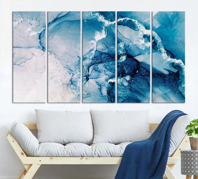 A set of Fluid Effect Wall Art Abstract Canvas prints, showcasing blue and white abstract designs on museum-quality canvas, is tastefully arranged on a dark wall.