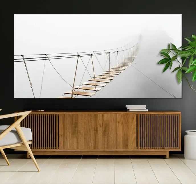 The Foggy and Wood Bridge Wall Art Canvas Print, with its UV-protective coating, elegantly adorns the living room wall. This museum-quality canvas depicting a foggy skywalk bridge exudes a captivating allure that remains timeless.