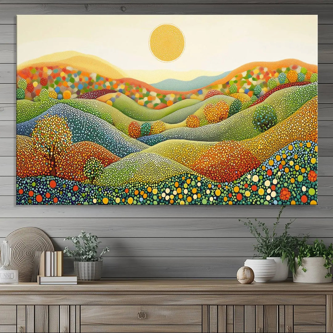 A framed Yayoi Kusama print featuring an abstract pointillism-inspired landscape of vibrant rolling hills and a sun.