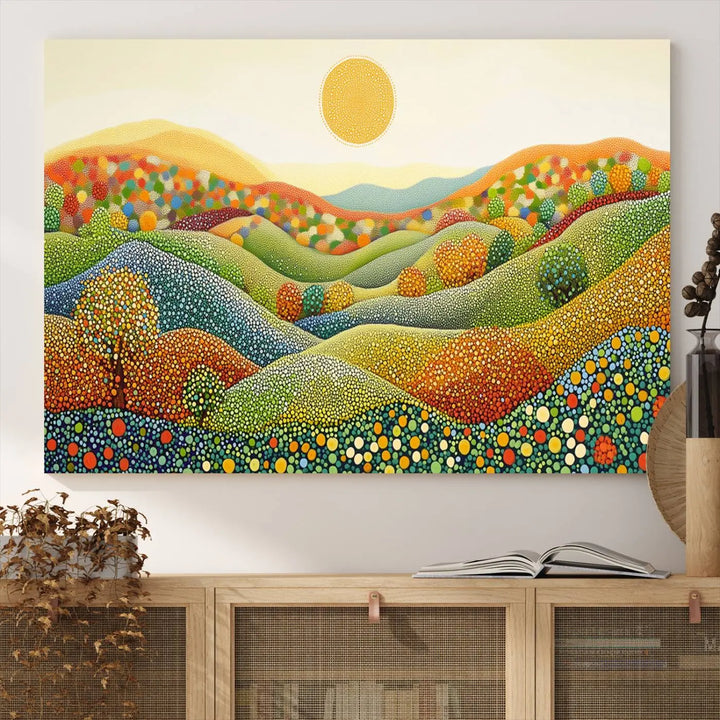 A framed Yayoi Kusama print featuring an abstract pointillism-inspired landscape of vibrant rolling hills and a sun.