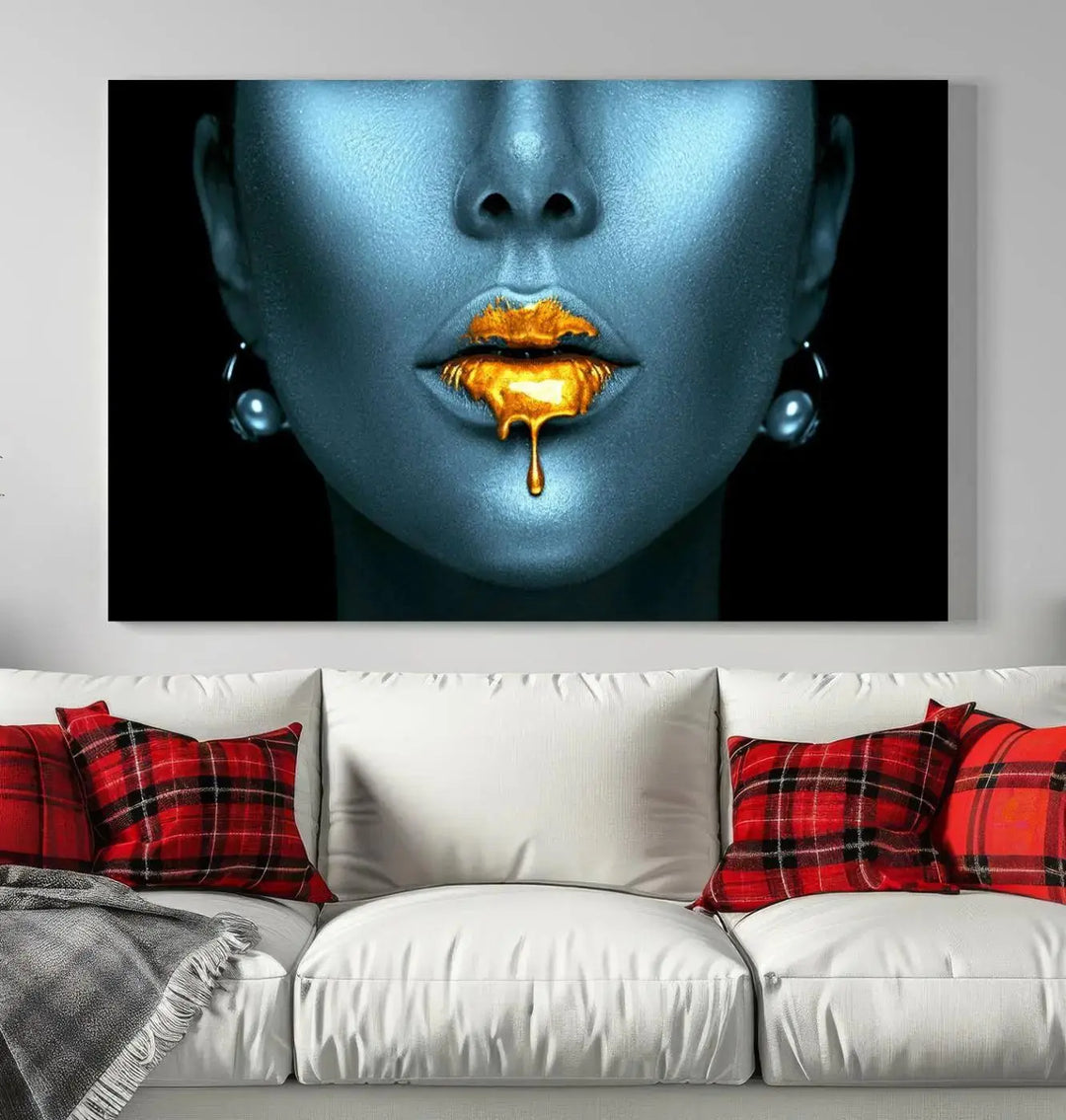 The Glitter Lips Wall Art Gold Lips Canvas Art Print in the contemporary living room showcases a blue-faced figure with glitter lips across three panels. The gallery-wrapped finish on high-quality polycotton canvas enhances the room's elegance.