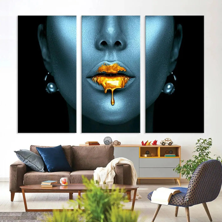 The Glitter Lips Wall Art Gold Lips Canvas Art Print in the contemporary living room showcases a blue-faced figure with glitter lips across three panels. The gallery-wrapped finish on high-quality polycotton canvas enhances the room's elegance.