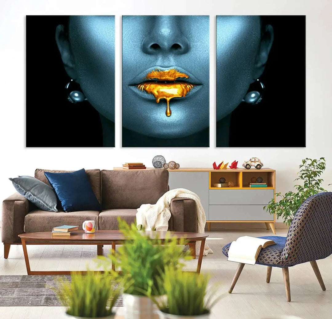 The Glitter Lips Wall Art Gold Lips Canvas Art Print in the contemporary living room showcases a blue-faced figure with glitter lips across three panels. The gallery-wrapped finish on high-quality polycotton canvas enhances the room's elegance.