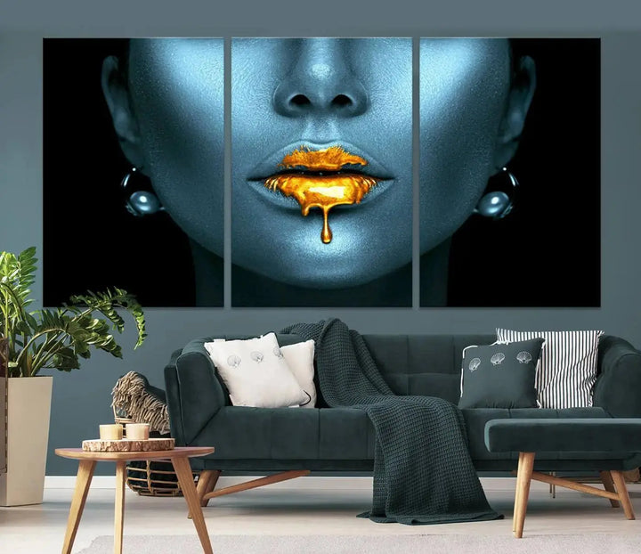 The Glitter Lips Wall Art Gold Lips Canvas Art Print in the contemporary living room showcases a blue-faced figure with glitter lips across three panels. The gallery-wrapped finish on high-quality polycotton canvas enhances the room's elegance.