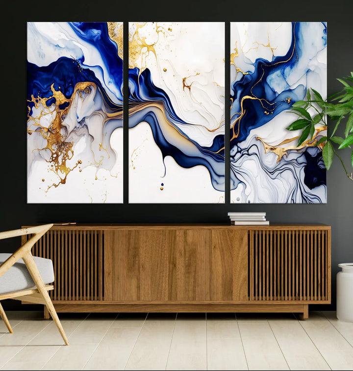 Enhance your modern home decor with the "Golden Cascades on Midnight Blue – Abstract Flowing Elegance" wall art canvas. This stunning piece features dynamic blue, gold, and white patterns. The triptych design comes framed and ready to hang, infusing any space with artistic expression.