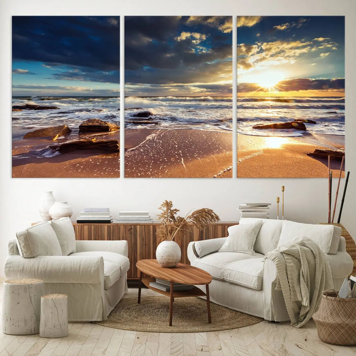 The cozy living room is enhanced by the Golden Hour Beach Sunset Canvas Triptych, featuring ocean waves and rocks.