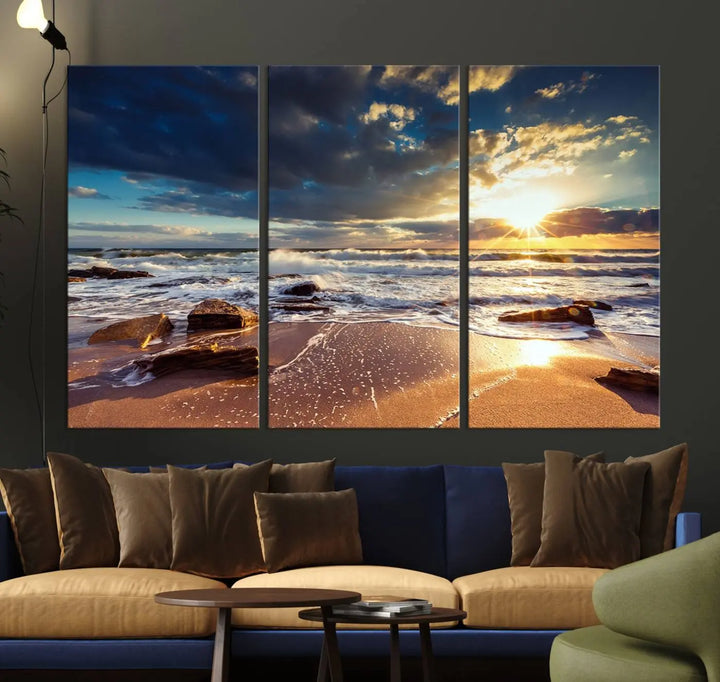 The cozy living room is enhanced by the Golden Hour Beach Sunset Canvas Triptych, featuring ocean waves and rocks.