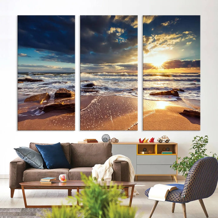 The cozy living room is enhanced by the Golden Hour Beach Sunset Canvas Triptych, featuring ocean waves and rocks.