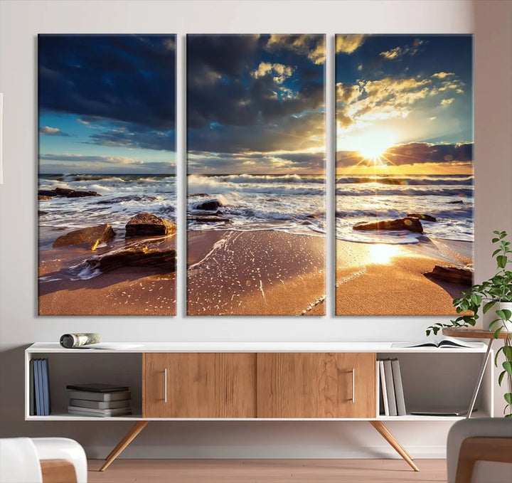 The cozy living room is enhanced by the Golden Hour Beach Sunset Canvas Triptych, featuring ocean waves and rocks.