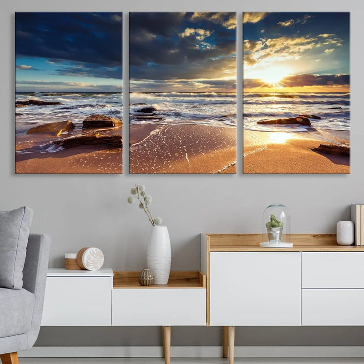 The cozy living room is enhanced by the Golden Hour Beach Sunset Canvas Triptych, featuring ocean waves and rocks.