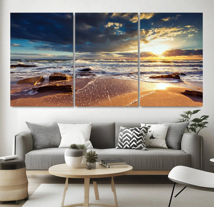 The cozy living room is enhanced by the Golden Hour Beach Sunset Canvas Triptych, featuring ocean waves and rocks.