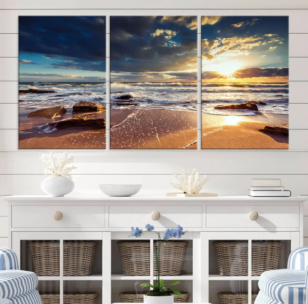 The cozy living room is enhanced by the Golden Hour Beach Sunset Canvas Triptych, featuring ocean waves and rocks.