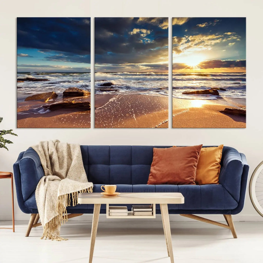 The cozy living room is enhanced by the Golden Hour Beach Sunset Canvas Triptych, featuring ocean waves and rocks.