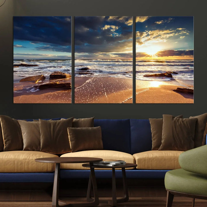 The cozy living room is enhanced by the Golden Hour Beach Sunset Canvas Triptych, featuring ocean waves and rocks.