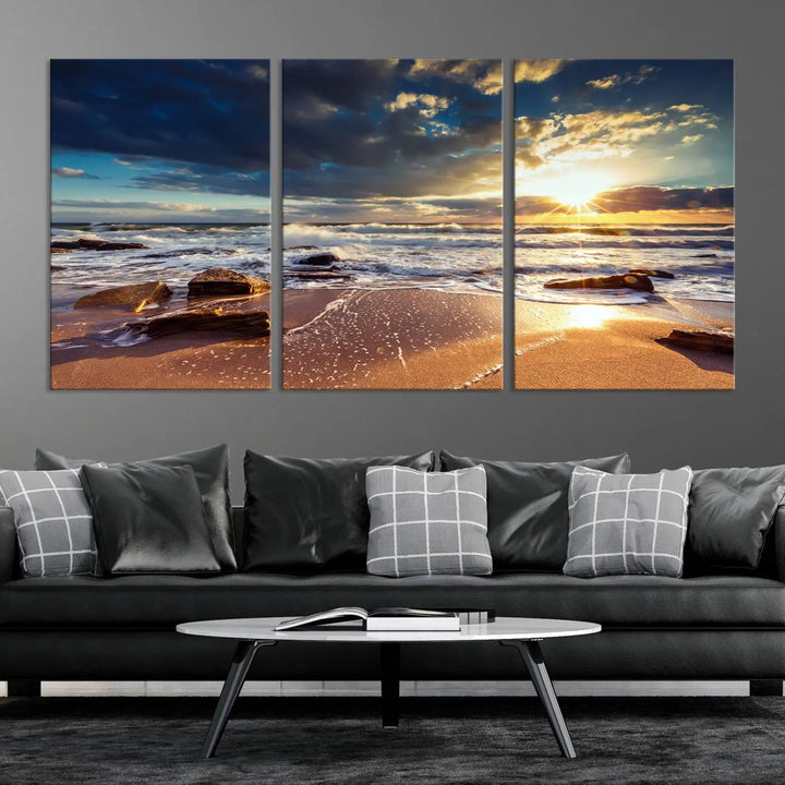 The cozy living room is enhanced by the Golden Hour Beach Sunset Canvas Triptych, featuring ocean waves and rocks.