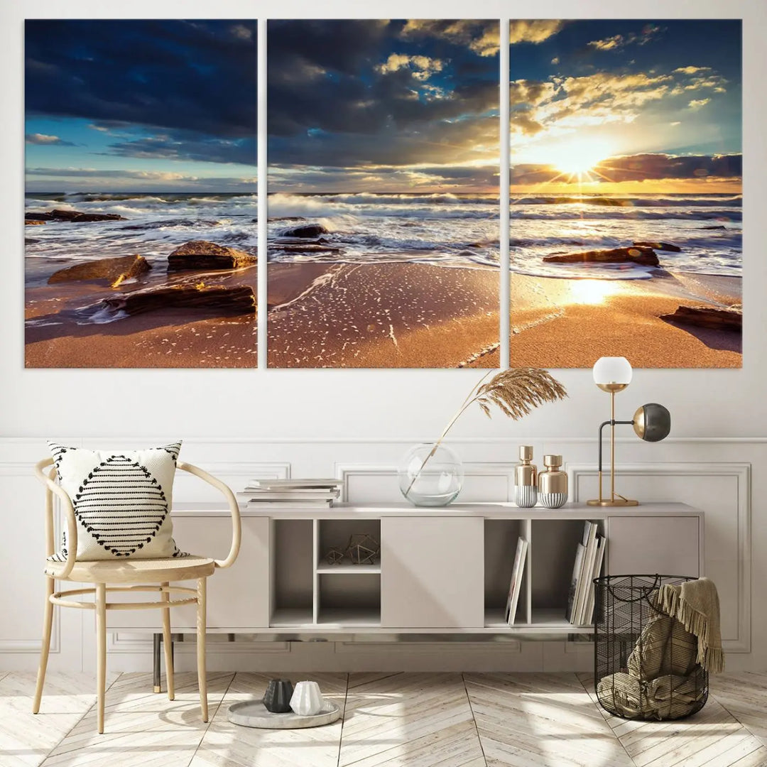 The cozy living room is enhanced by the Golden Hour Beach Sunset Canvas Triptych, featuring ocean waves and rocks.