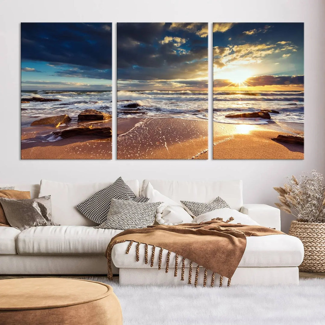 The cozy living room is enhanced by the Golden Hour Beach Sunset Canvas Triptych, featuring ocean waves and rocks.