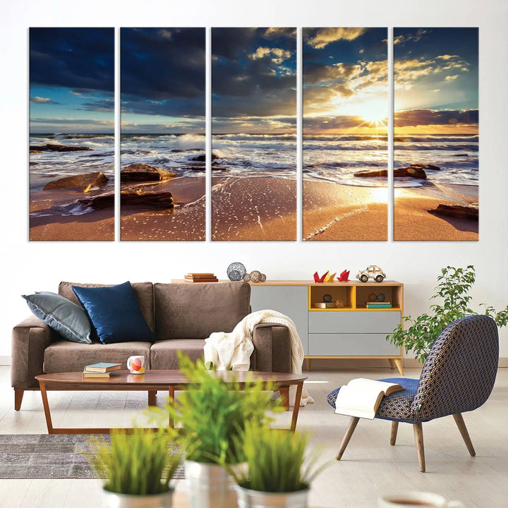 The cozy living room is enhanced by the Golden Hour Beach Sunset Canvas Triptych, featuring ocean waves and rocks.