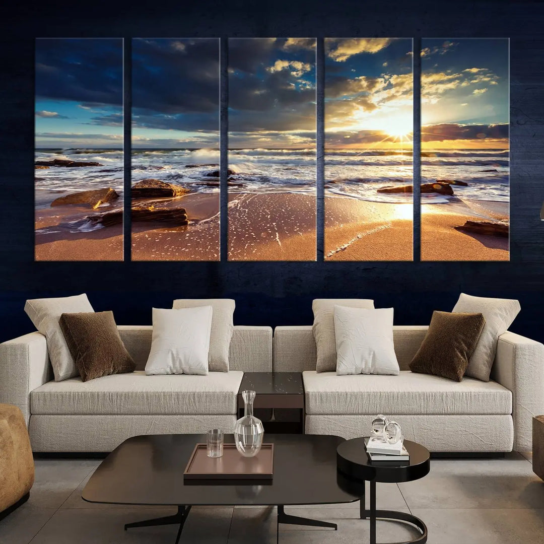 The cozy living room is enhanced by the Golden Hour Beach Sunset Canvas Triptych, featuring ocean waves and rocks.