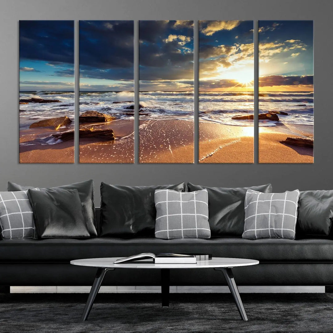 The cozy living room is enhanced by the Golden Hour Beach Sunset Canvas Triptych, featuring ocean waves and rocks.