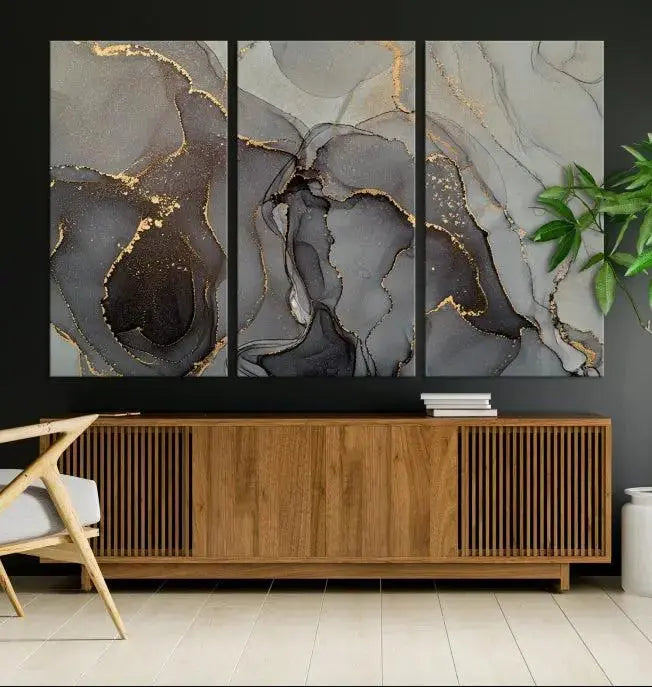 The Gray Marble Fluid Effect Wall Art Abstract Canvas Wall Art Print is a museum-quality canvas featuring triptych abstract art with swirling gray and gold patterns. Complete with a UV-protective coating, this piece of artwork arrives ready to hang, effortlessly elevating your living space.