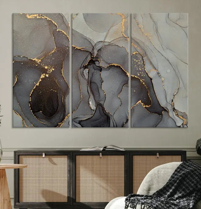 The Gray Marble Fluid Effect Wall Art Abstract Canvas Wall Art Print is a museum-quality canvas featuring triptych abstract art with swirling gray and gold patterns. Complete with a UV-protective coating, this piece of artwork arrives ready to hang, effortlessly elevating your living space.