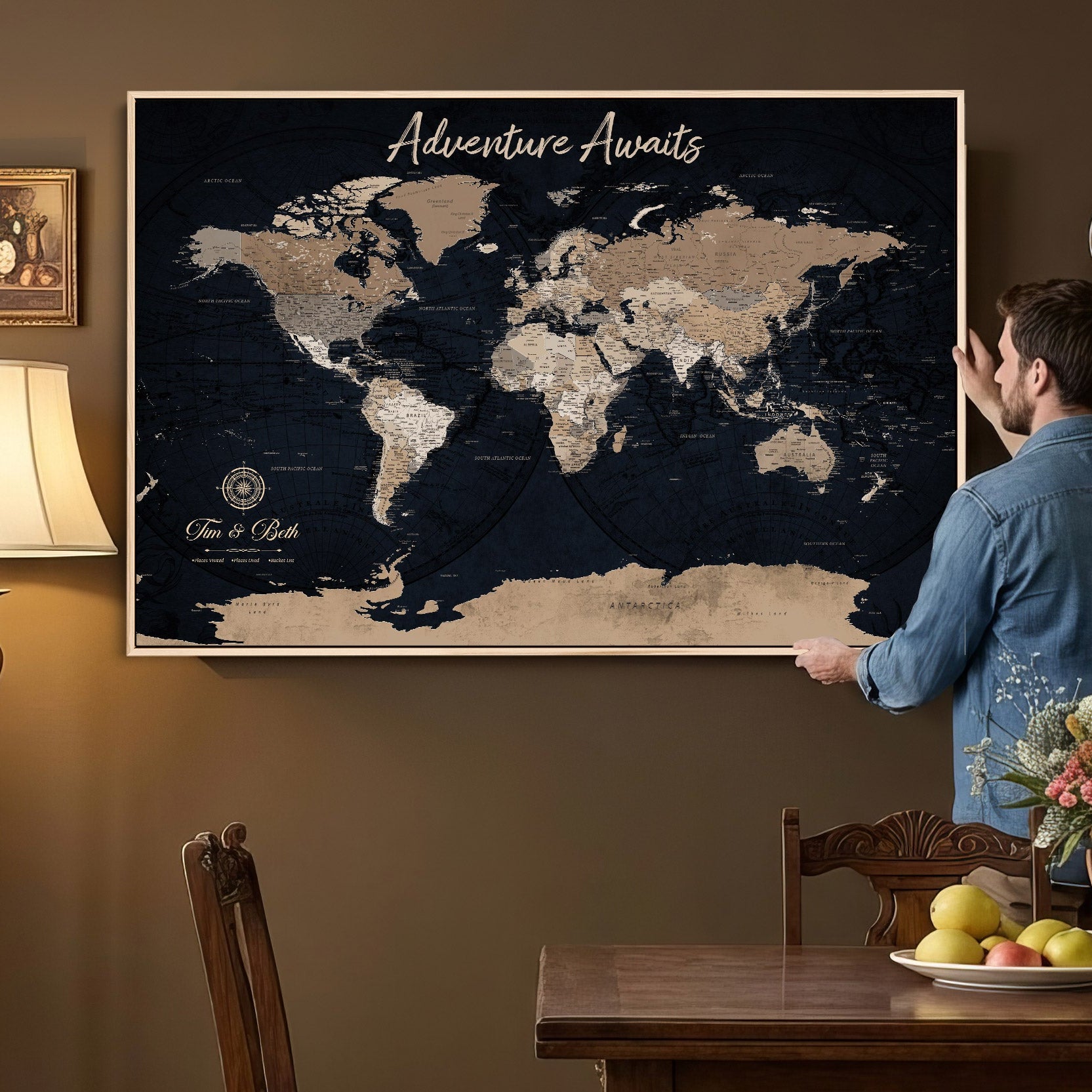 Man looking at a world map on the wall in a room with a wooden table and chair.