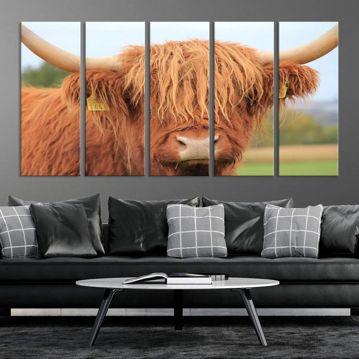 A multi-panel canvas set artwork features a close-up of a Highland cow with long horns and shaggy fur, displayed gallery-wrapped on museum-quality canvas with UV-protective coating. It hangs elegantly on a dark wall.