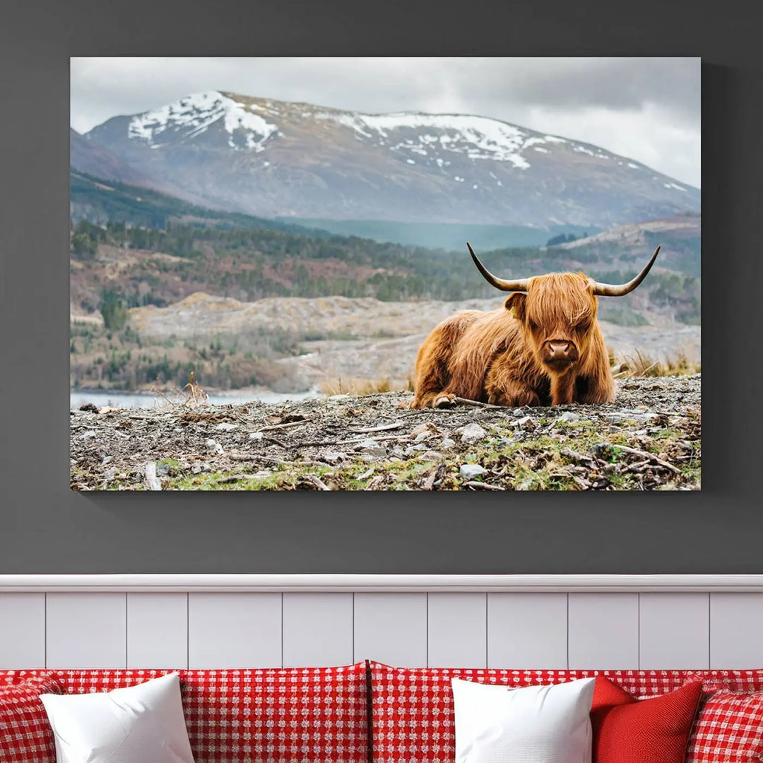 The Highland Cow Horn Farm Wall Art Canvas Print showcases a serene scene of a highland cow resting with snow-capped mountains in the background. This three-panel, museum-quality canvas features a UV-protective coating and is ready to hang.