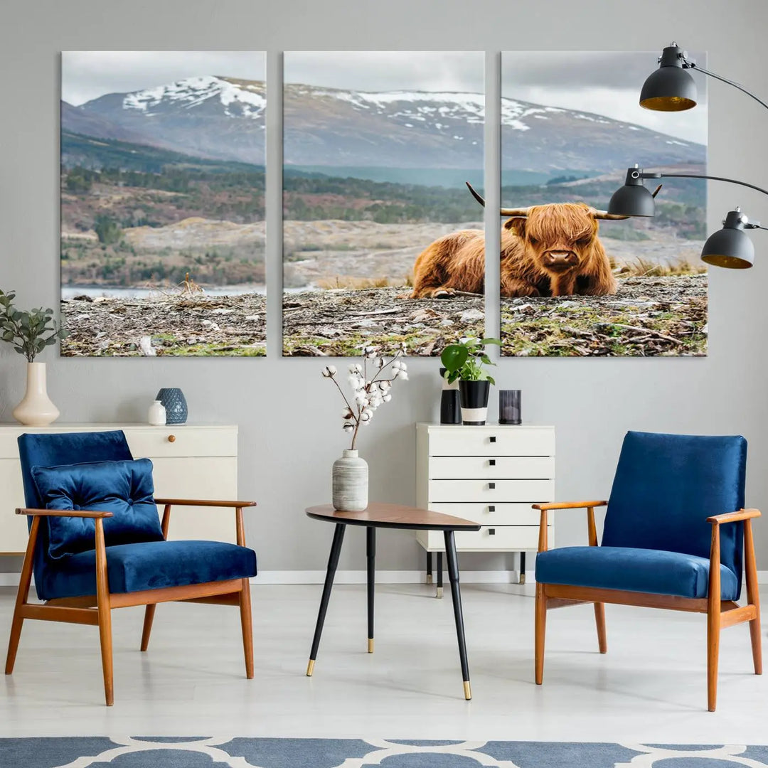 The Highland Cow Horn Farm Wall Art Canvas Print showcases a serene scene of a highland cow resting with snow-capped mountains in the background. This three-panel, museum-quality canvas features a UV-protective coating and is ready to hang.