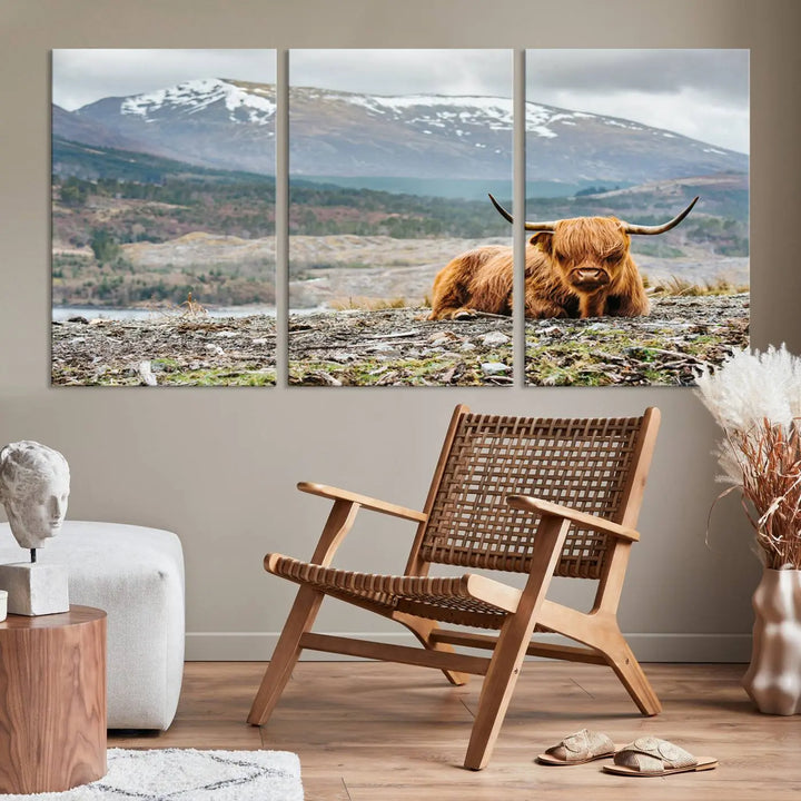 The Highland Cow Horn Farm Wall Art Canvas Print showcases a serene scene of a highland cow resting with snow-capped mountains in the background. This three-panel, museum-quality canvas features a UV-protective coating and is ready to hang.